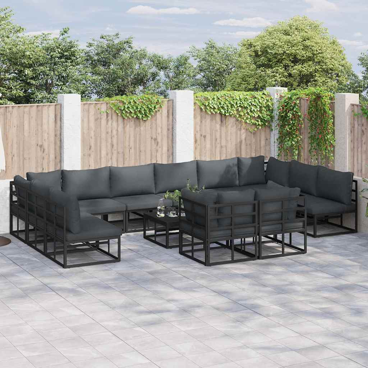 Outdoor-Sitzgruppe mit dunkelgrauen Kissen. Das Set umfasst ein großes Ecksofa, Einzelstühle und einen kleinen Tisch.