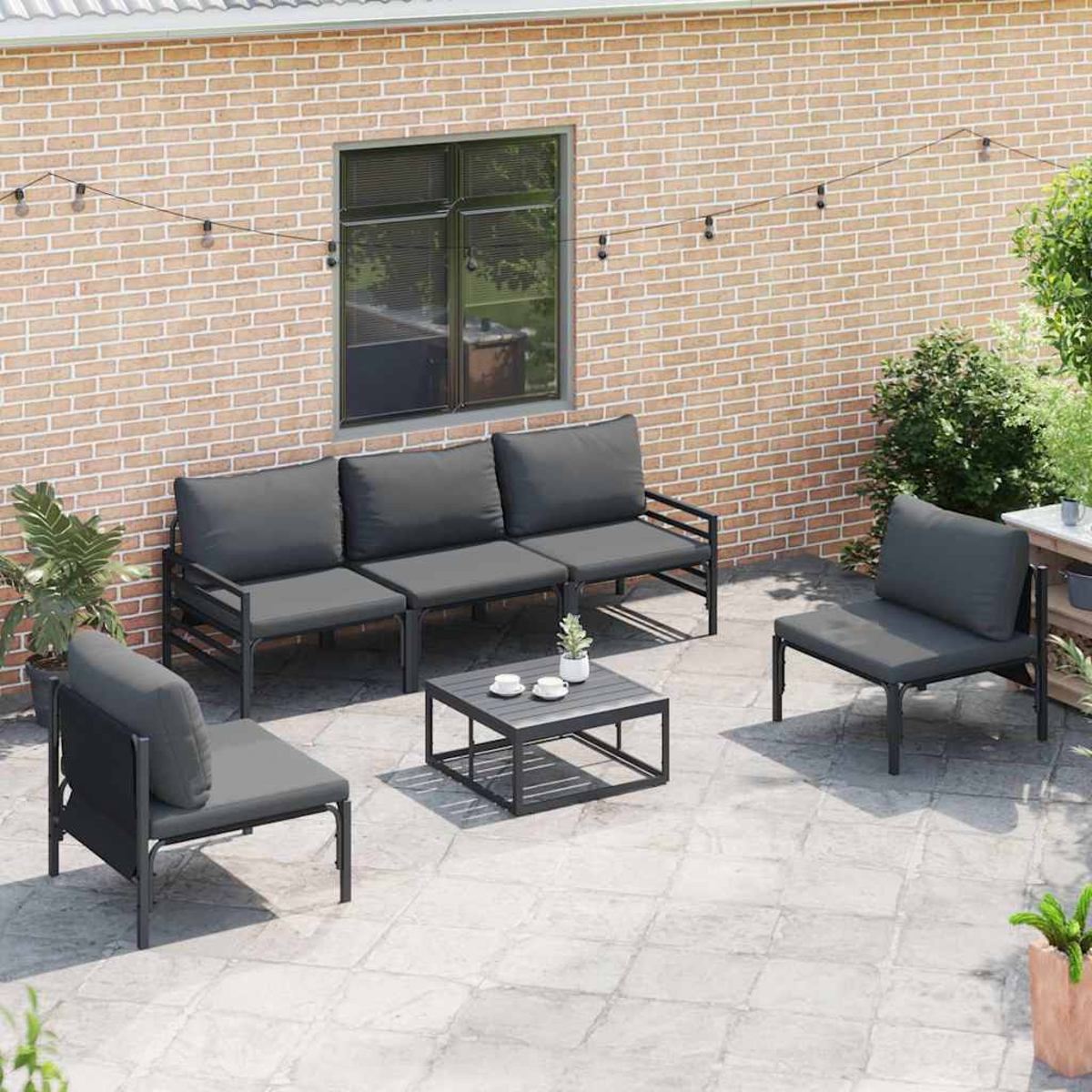 Gartenmöbel-Set: Sofa, zwei Sessel und Couchtisch. Hintergrund: Backsteinmauer.
