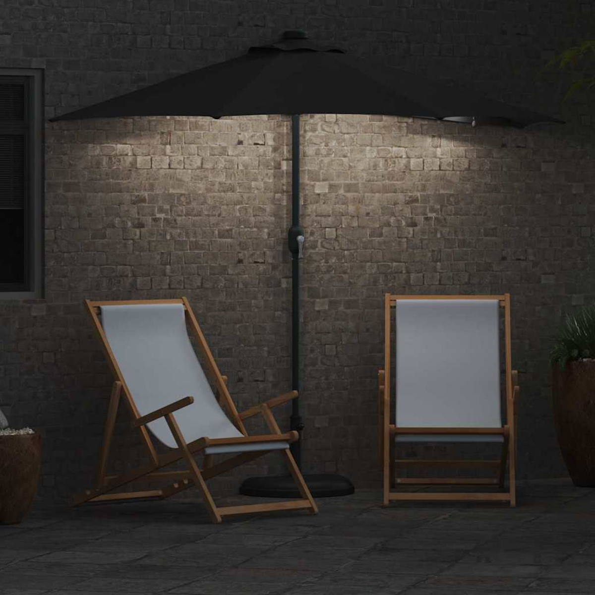Due sedie in legno con tessuto grigio sono sotto un ombrello nero. Un muro di mattoni fa da sfondo. La scena è illuminata di notte.
