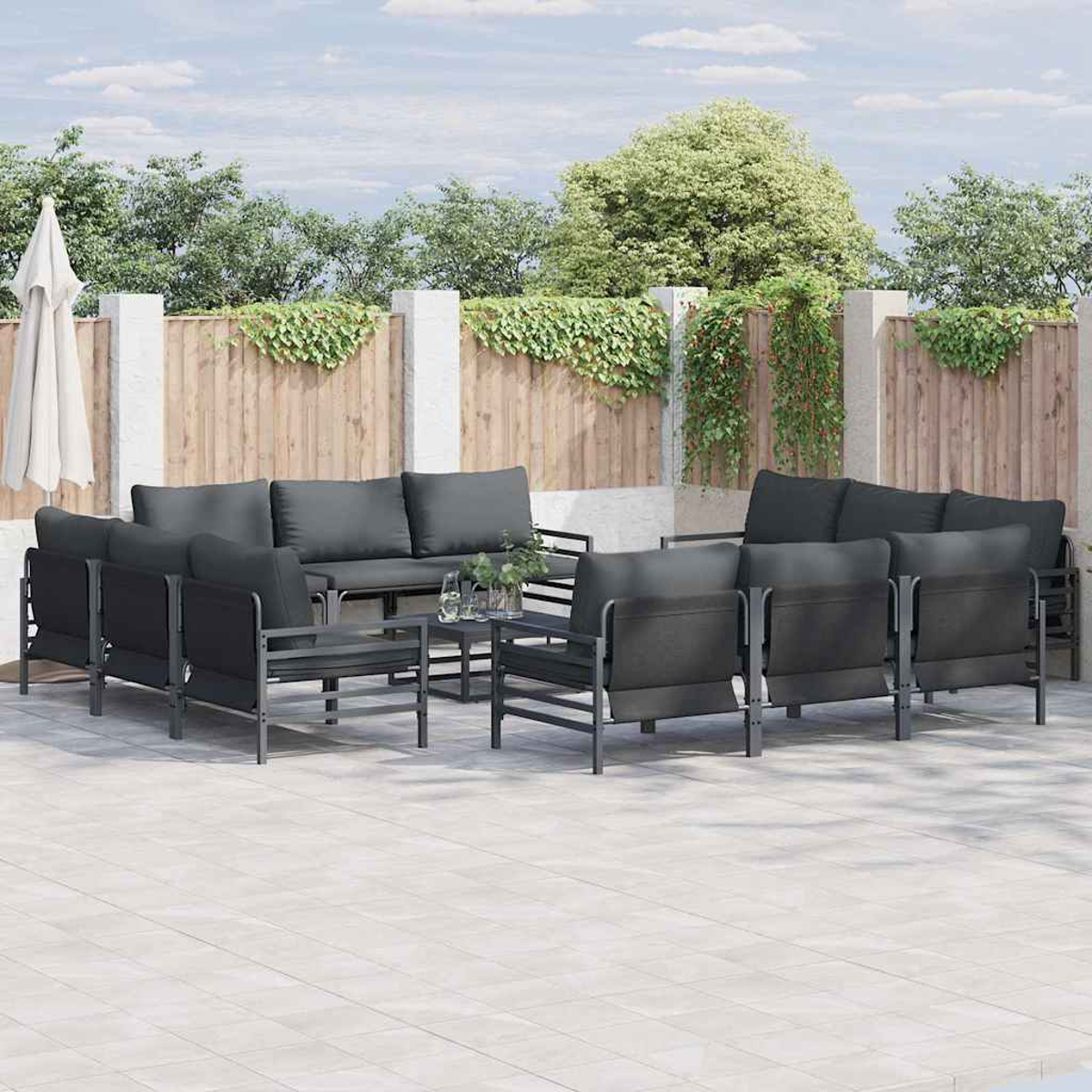 Outdoor-Terrassenset mit dunkelgrauen Kissen. Beinhaltet Stühle, Sofas und einen kleinen Tisch, alles auf einer gefliesten Terrasse.
