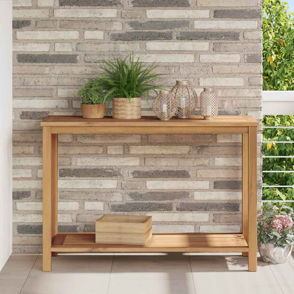Mesa de madera con plantas y decoraciones contra una pared de ladrillos. Una caja de madera debajo. Balcón con follaje a la derecha.