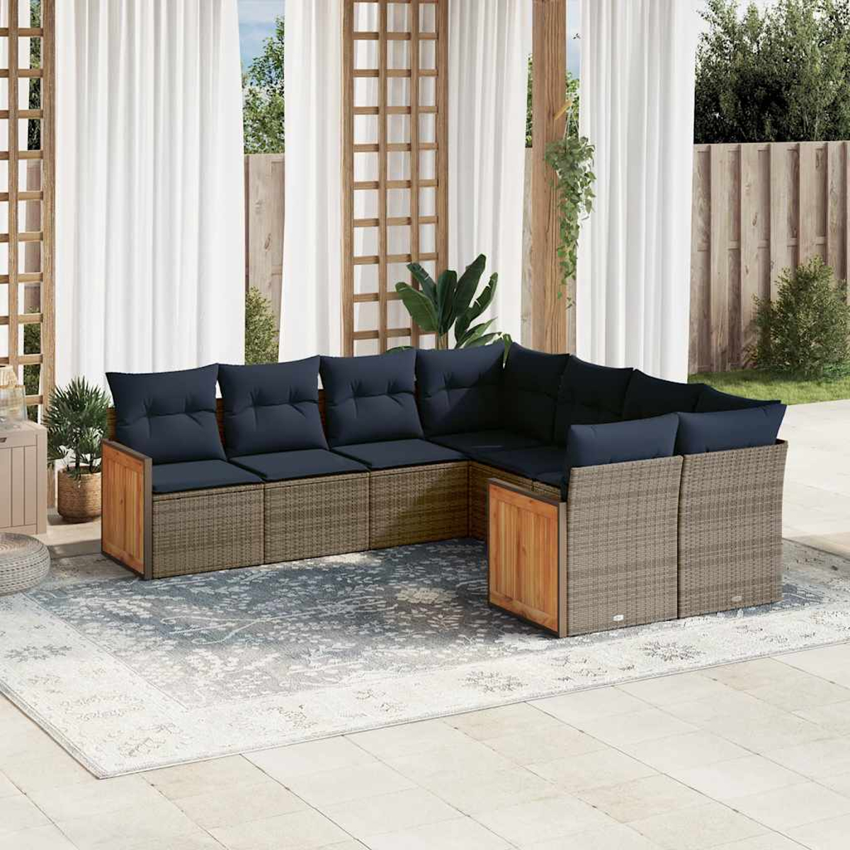 Ein Ecksofa für den Außenbereich mit marineblauen Kissen und einem korbähnlichen Untergestell. Das Sofa steht auf einem gemusterten Teppich, in der Nähe von Vorhängen.