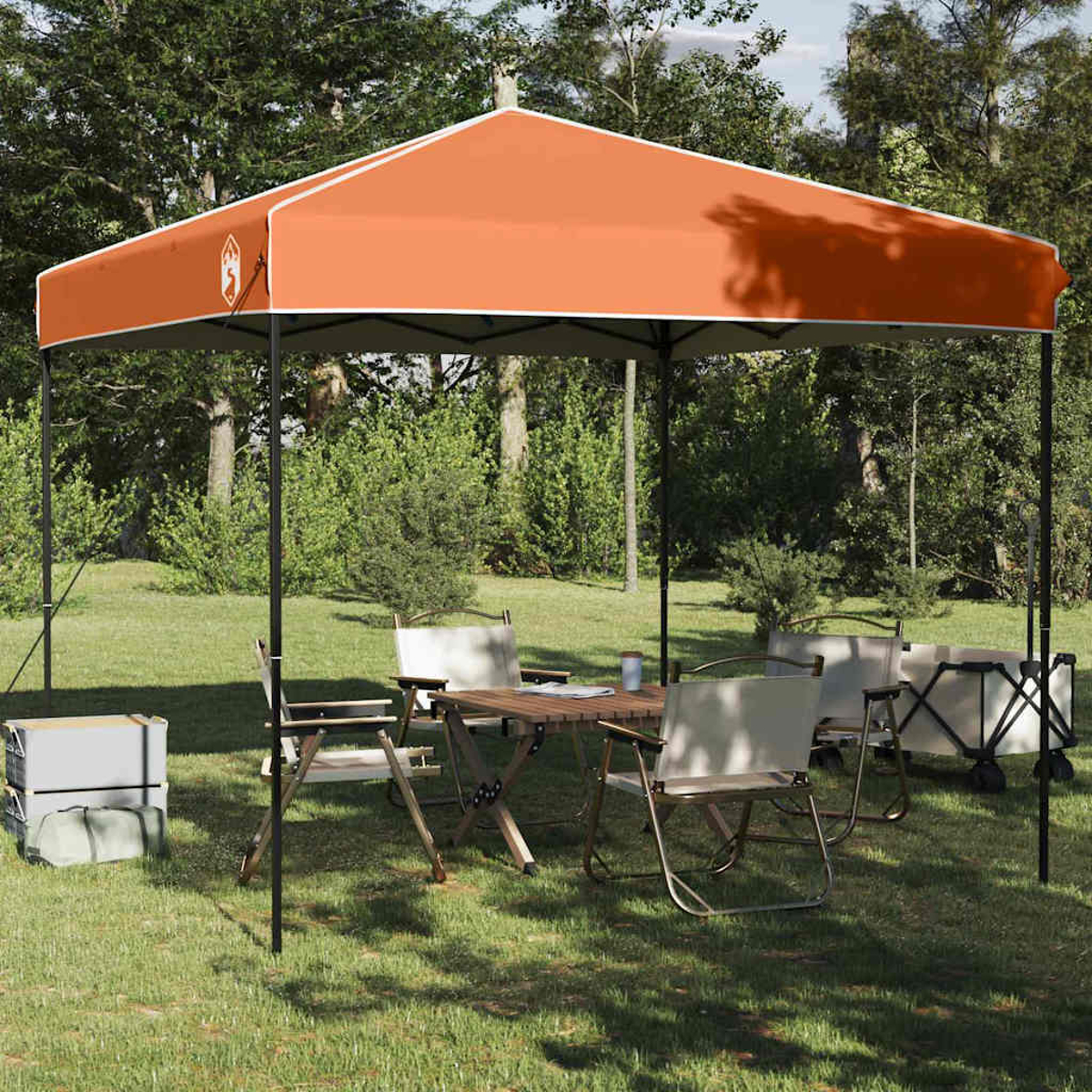 Orangefarbenes Baldachinzelt mit Tisch und Stühlen auf Rasen aufgestellt. Bäume im Hintergrund. Campingausrüstung ist vorhanden.