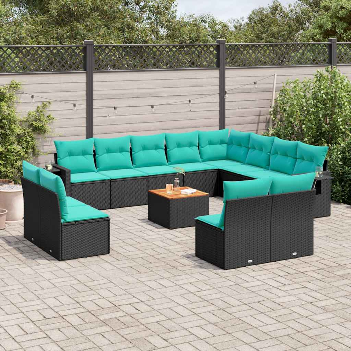 Gartenmöbel-Set: schwarze Korbsessel mit türkisfarbenen Kissen auf einer Terrasse, kleiner Holztisch und Zaun im Hintergrund.