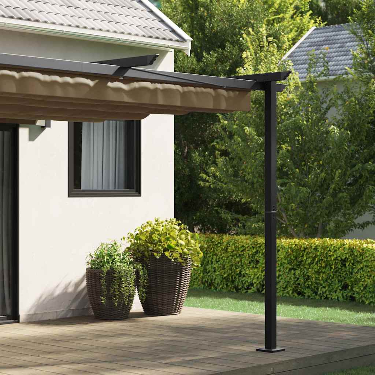 Eine Terrasse mit Markise, zwei Topfpflanzen und einem schwarzen Pfosten. Im Hintergrund ein weißes Haus, umgeben von grünen Büschen und Bäumen.