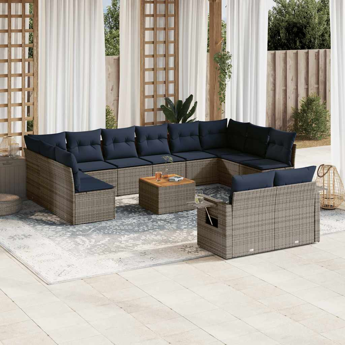 Outdoor-Ecksofa mit marineblauen Kissen und einem Holztisch auf einem gemusterten Teppich. Weiße Vorhänge und Grün im Hintergrund.