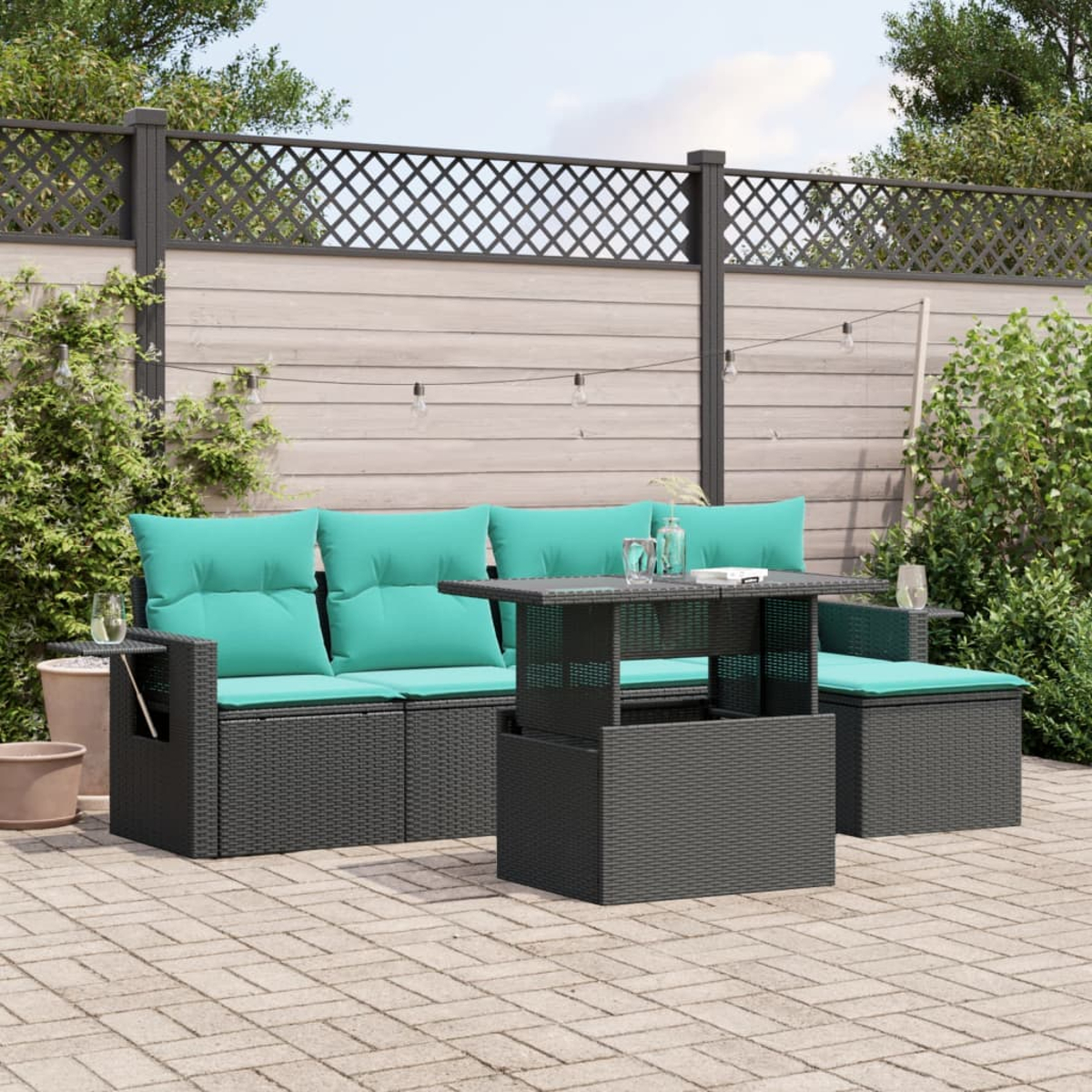 Garten-Terrassenset mit tealfarbenen Kissen, einem Tisch mit Hubfunktion und Zaun im Hintergrund. Das Set steht auf einer Steinterrasse.