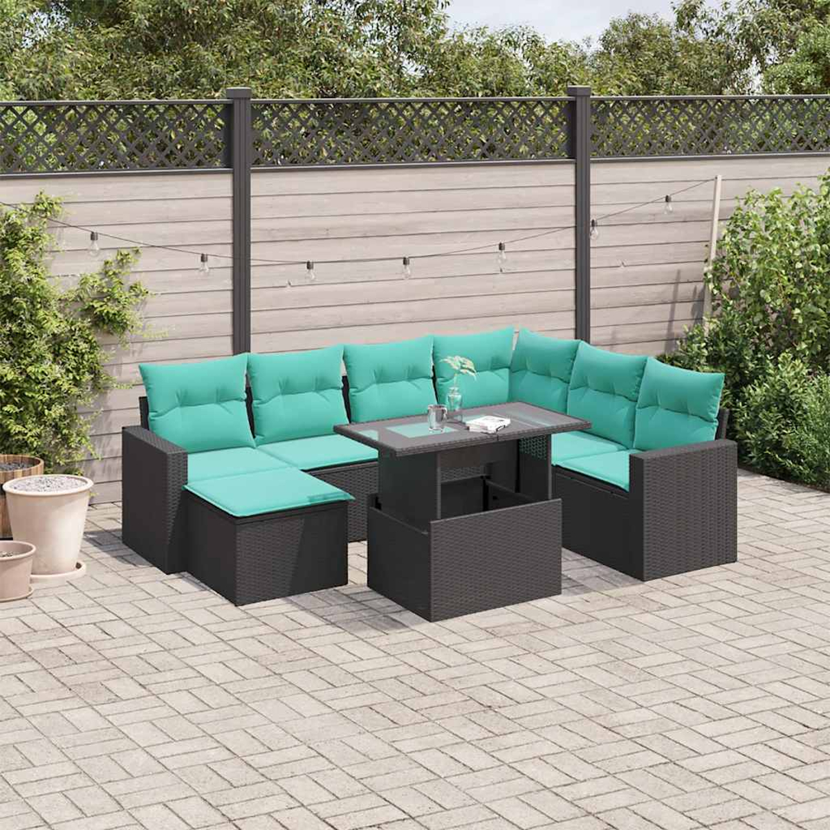 Garten-Sitzgruppe mit türkisfarbenen Kissen, einem Tisch mit Hubfunktion, auf einer Ziegelpflasterung. Hintergrund: Holzzaun und Grün.