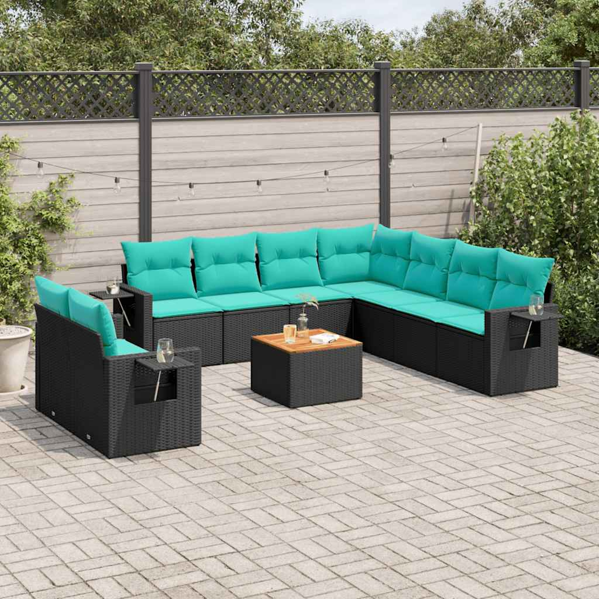 Outdoor-Ecksofa-Set mit türkisfarbenen Kissen auf einer Ziegelterrasse. Inklusive Couchtisch und Beistelltischen. Zaun und Grün im Hintergrund.