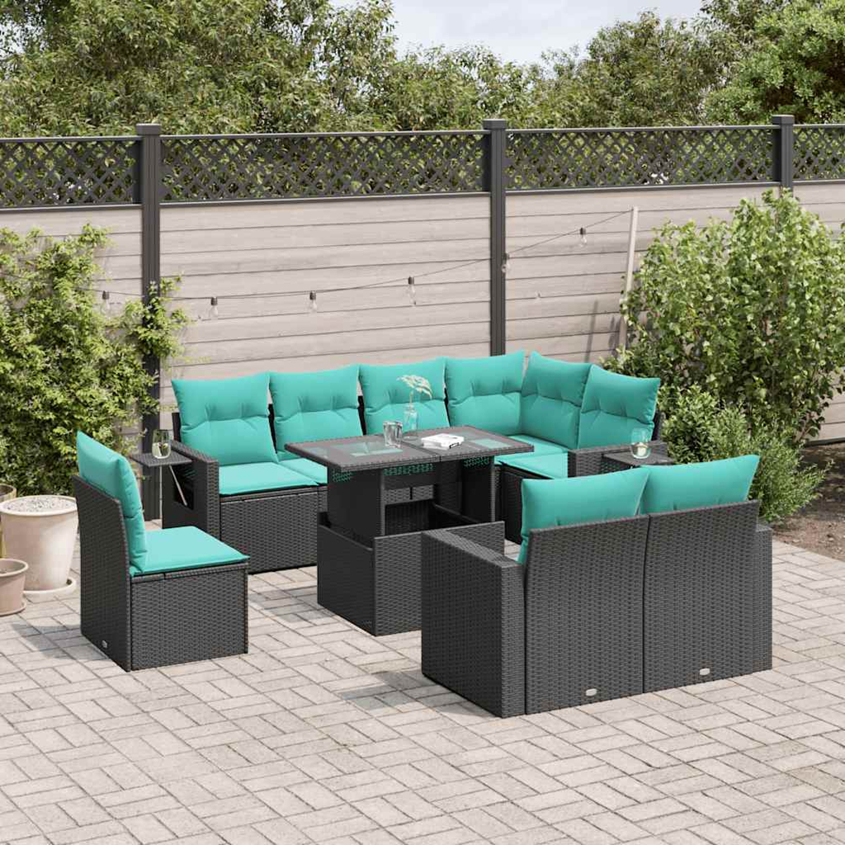 Garten-Sitzgruppe mit tealfarbenen Kissen. Beinhaltet ein Ecksofa, Stühle und einen Tisch auf einer Terrasse. Im Hintergrund ist ein Zaun und Grün.