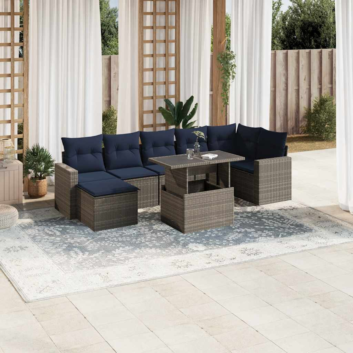Outdoor-Terrassenset mit blauen Kissen. Ein grauer Tisch ist von modularen Sitzgelegenheiten und einem Teppich umgeben.