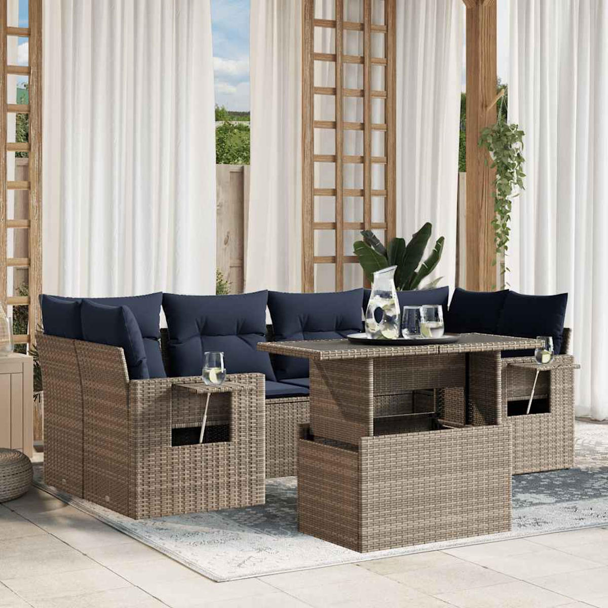 Gartenmöbel-Set. Korbbasofa mit marineblauen Kissen, Couchtisch und Teppich. Weiße Vorhänge und eine Pflanze.