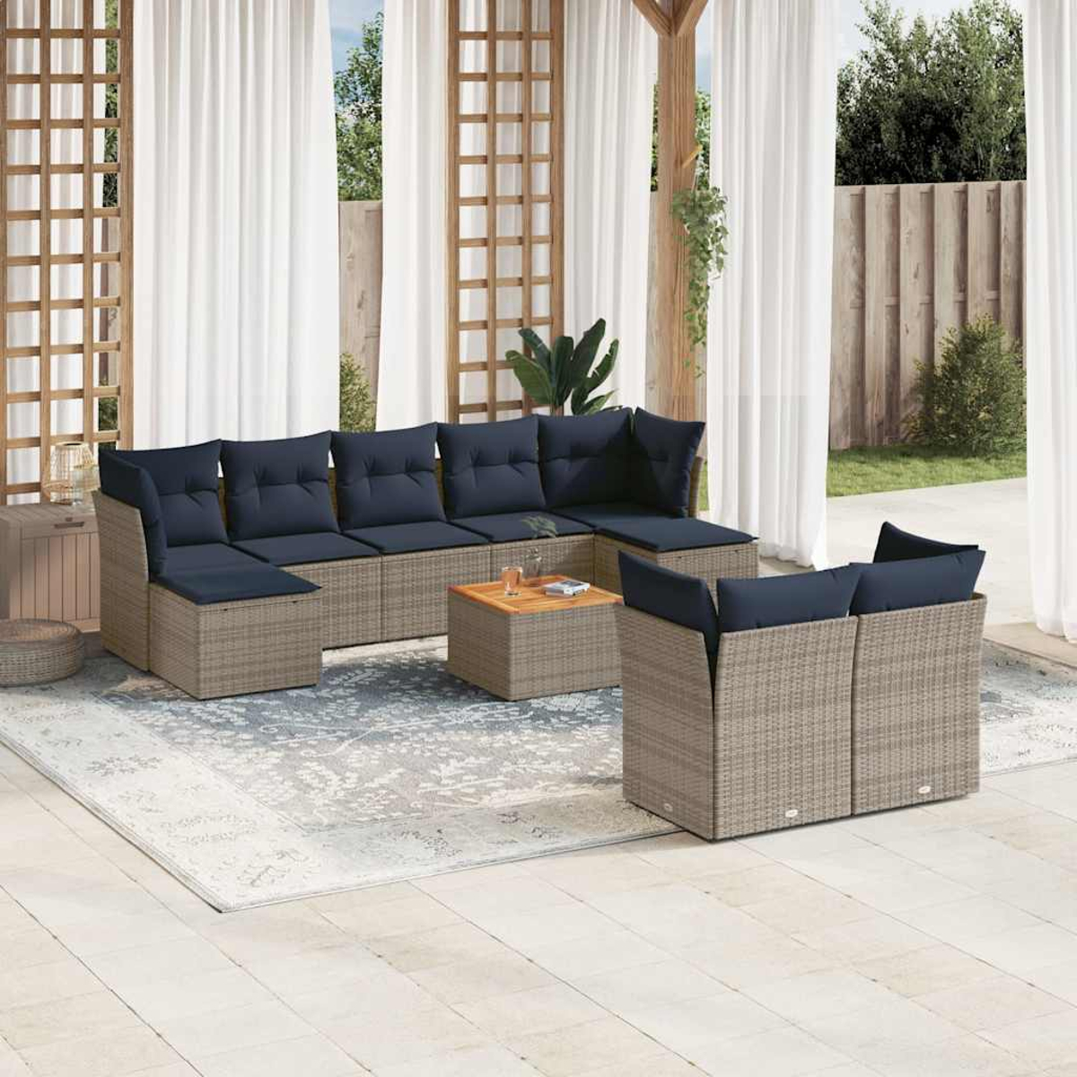 Gartenmöbelset mit blauen Kissen. Enthält ein Ecksofa, zwei Stühle und einen Couchtisch auf einem gemusterten Teppich.