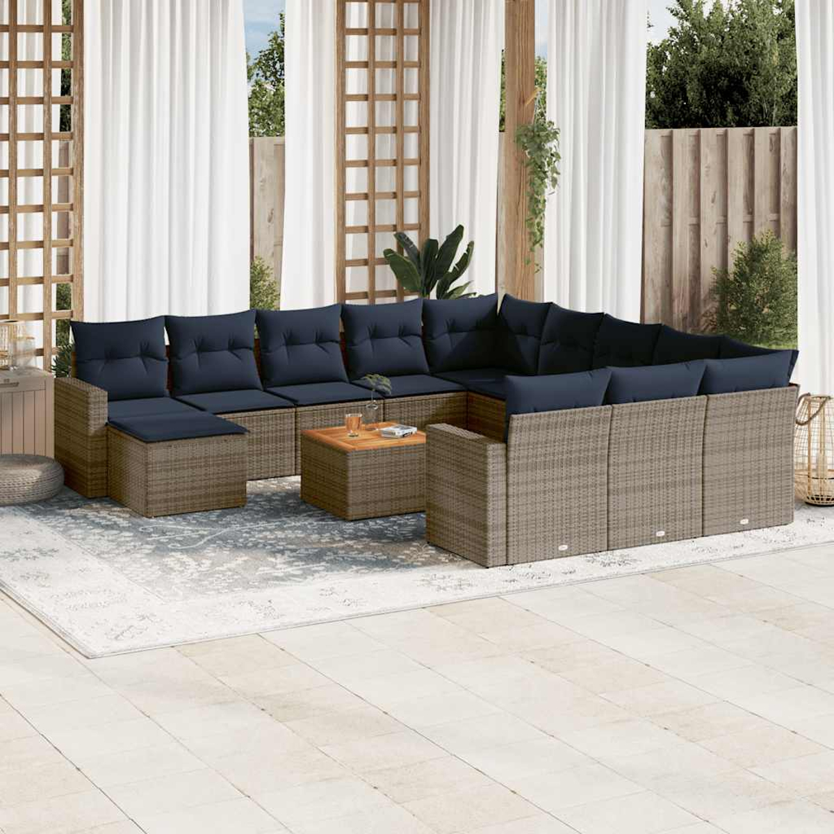 Outdoor-Ecksofa mit marineblauen Kissen und einem Couchtisch auf einem Teppich. Weiße Vorhänge und Holzgitter im Hintergrund.