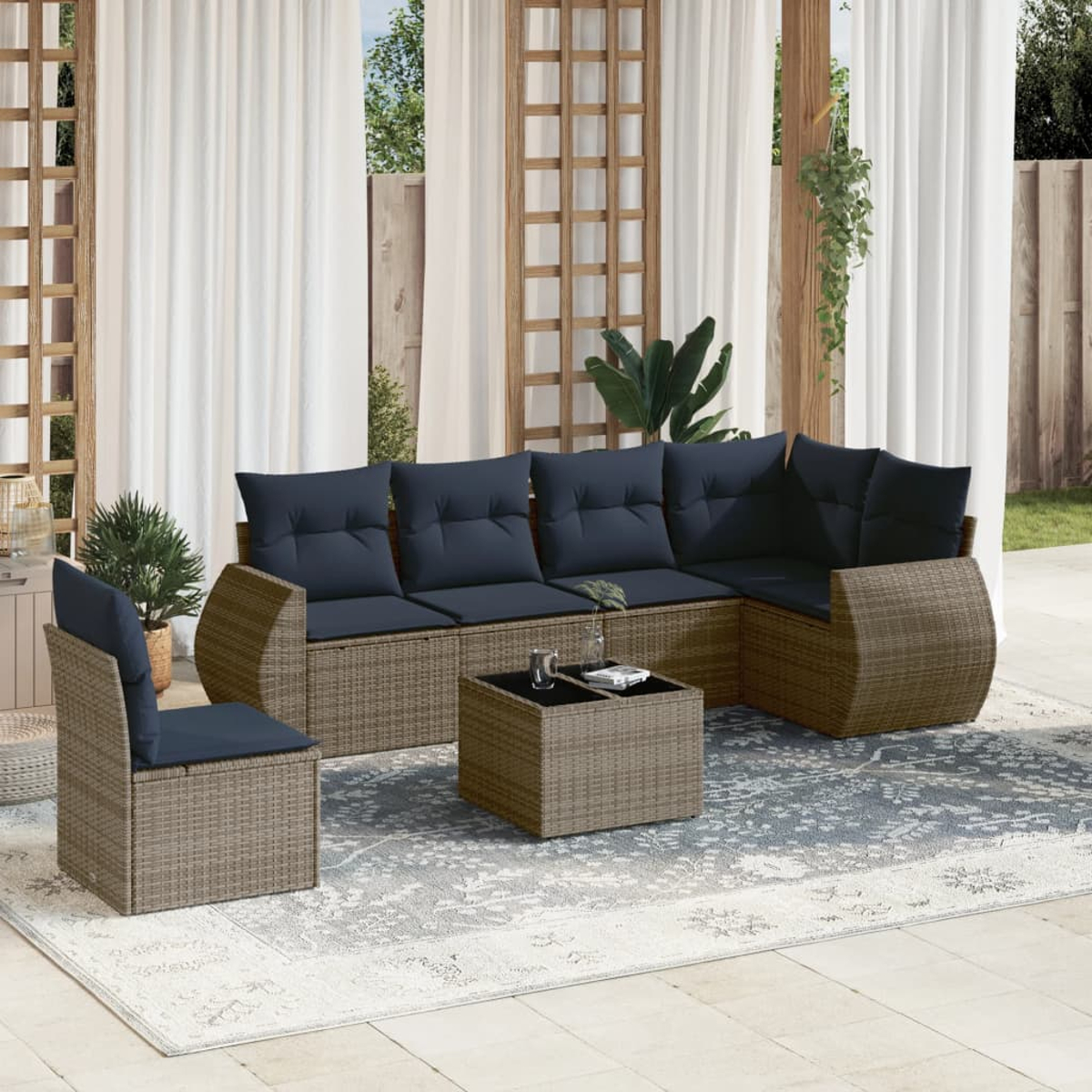 Garten-Terrassenset: gewebtes braunes Ecksofa mit marinefarbenen Kissen, passender Stuhl, quadratischer Couchtisch. Weiße Vorhänge und Teppich.