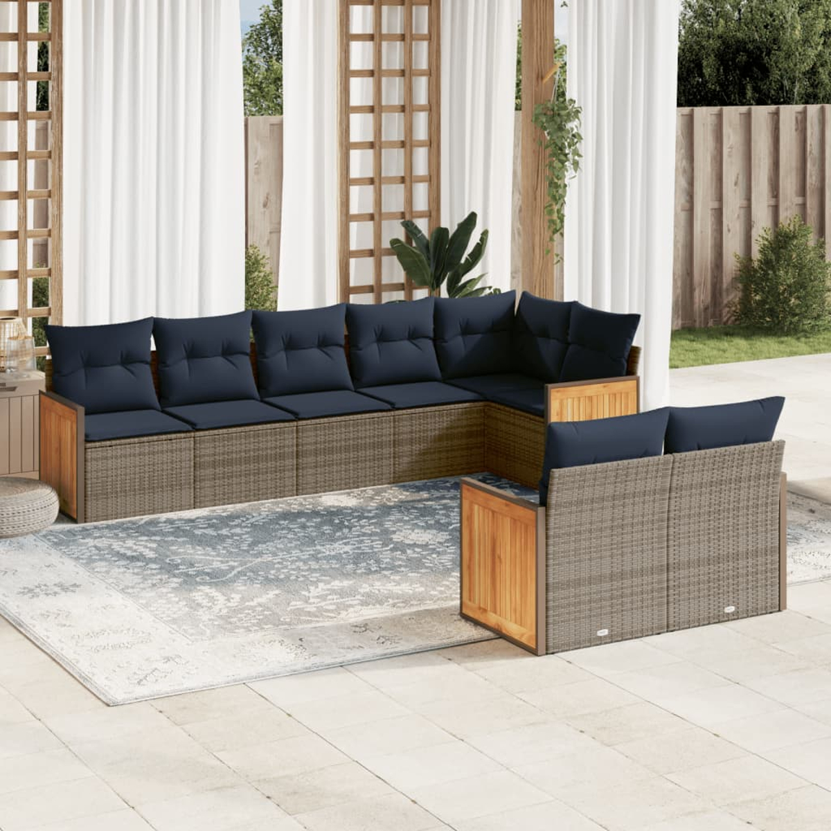 Outdoor-Ecksofa mit marineblauen Kissen. Wicker-Basis mit Holzakzenten. Auf einer Terrasse mit gemustertem Teppich.