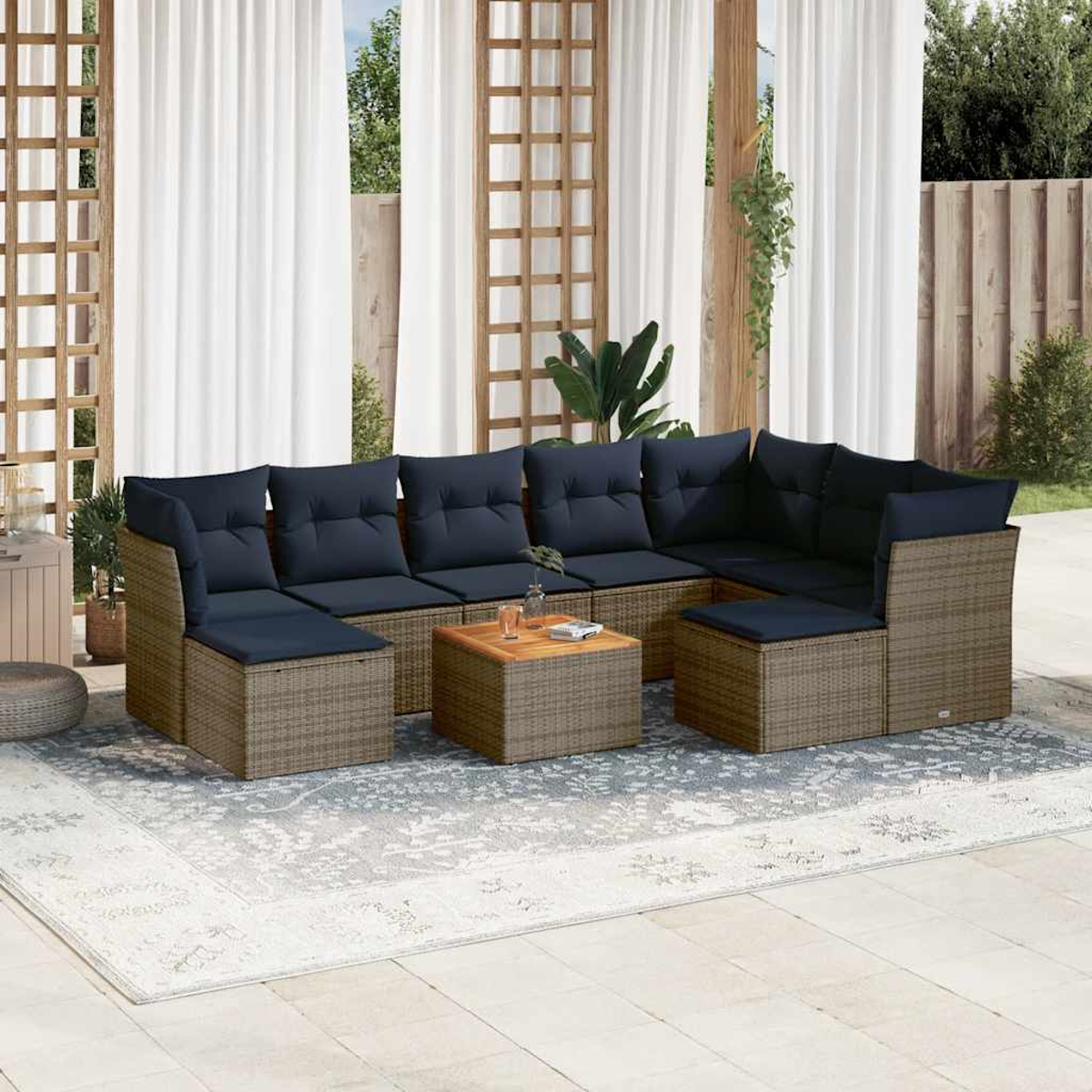 Outdoor-Ecksofa mit blauen Kissen. Ein Couchtisch aus Holz steht auf einem gemusterten Teppich. Weiße Vorhänge und ein Holzzaun sind im Hintergrund.