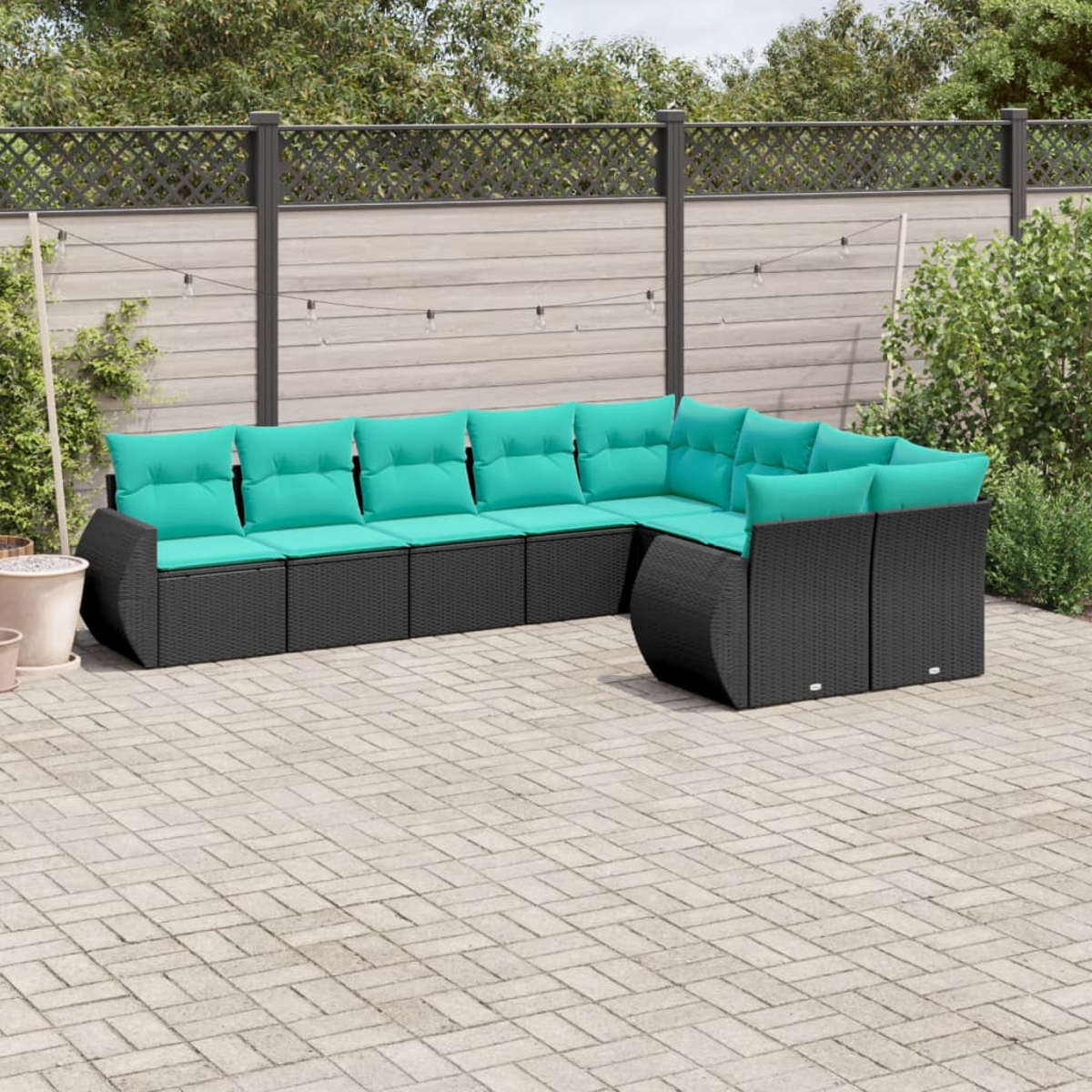 Ein Ecksofa mit teal farbenen Kissen steht im Freien. Ein Holzzaun und Grünzeug sind im Hintergrund. Lichterketten sind angebracht.