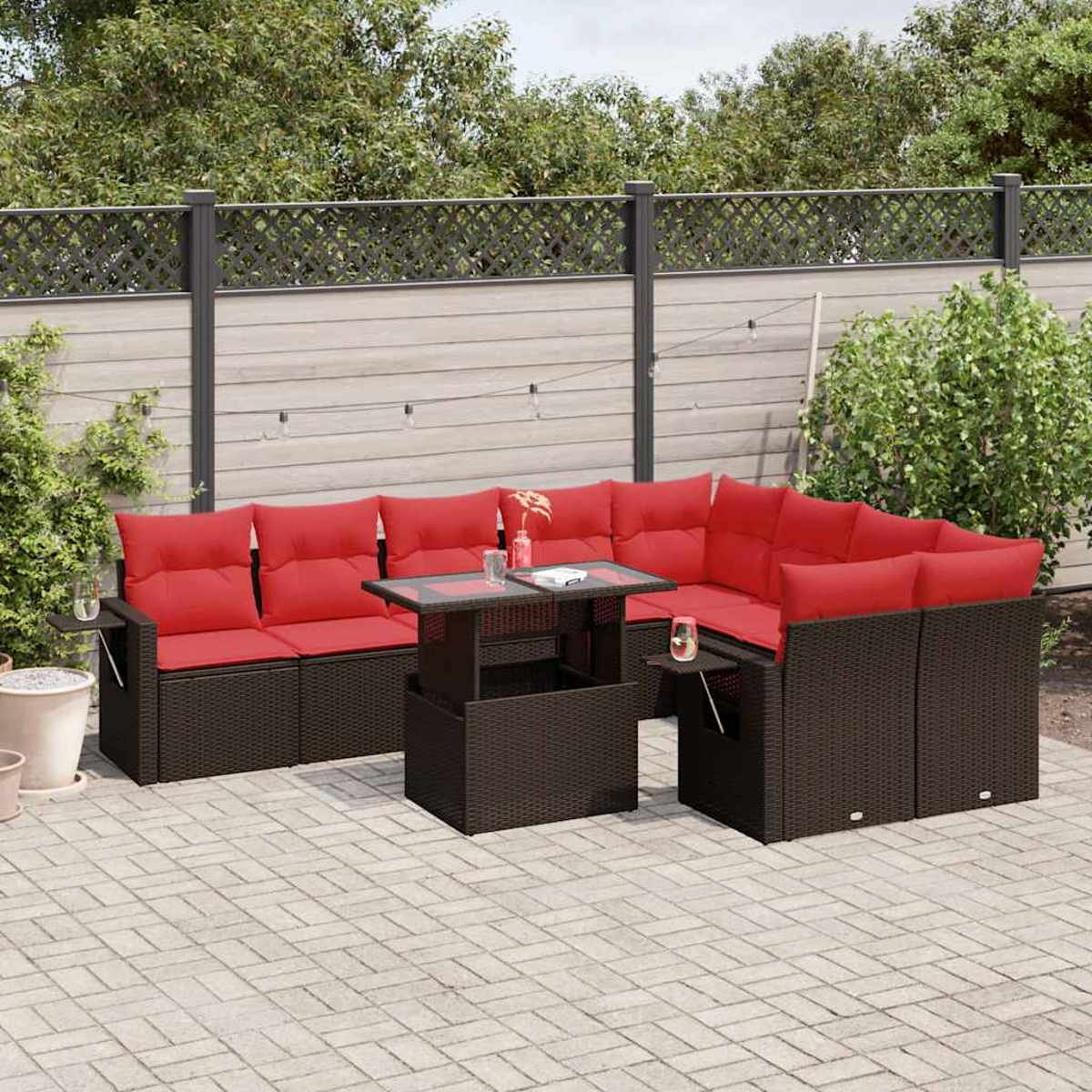 Gartenmöbel-Set mit roten Kissen, Glastisch und braunen Möbeln auf einer Ziegeloberfläche.