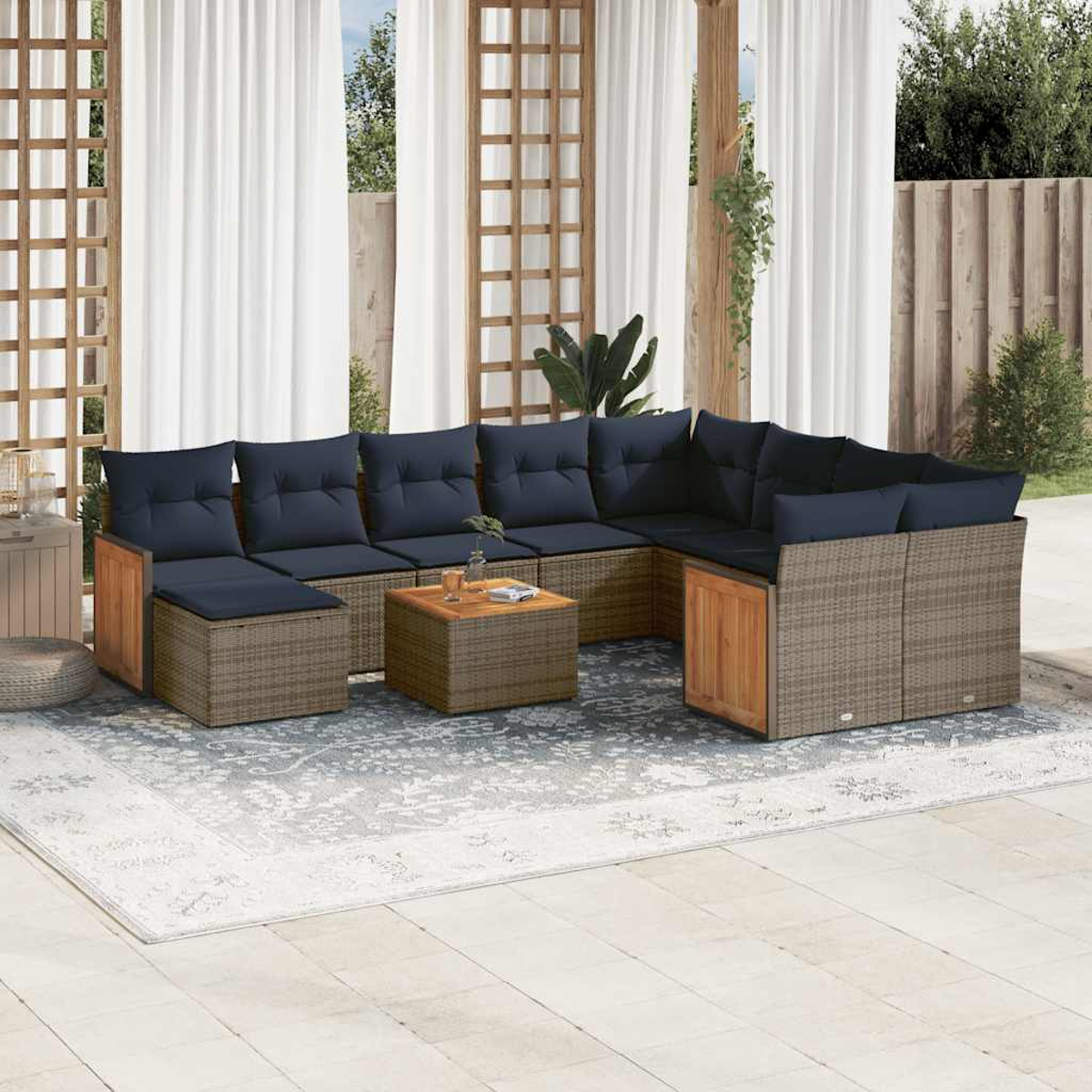 Outdoor-Ecksofa mit marineblauen Kissen, ein Holztisch auf einem gemusterten Teppich und weiße Vorhänge im Hintergrund.