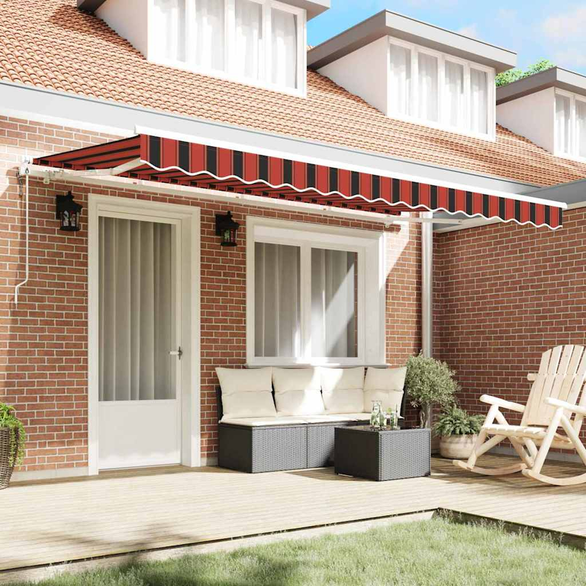 Ein Backsteinhaus mit Markise. Terrasse mit Sofa, Schaukelstuhl und Tisch. Grünes Gras im Vordergrund.