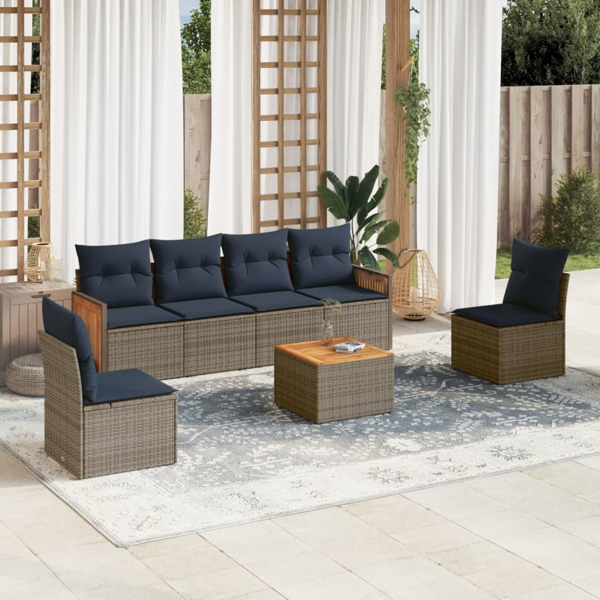 Terrassenset mit Sofa, zwei Stühlen und Couchtisch. Blaue Kissen und Korbmöbel. Weiße Vorhänge und Teppich.