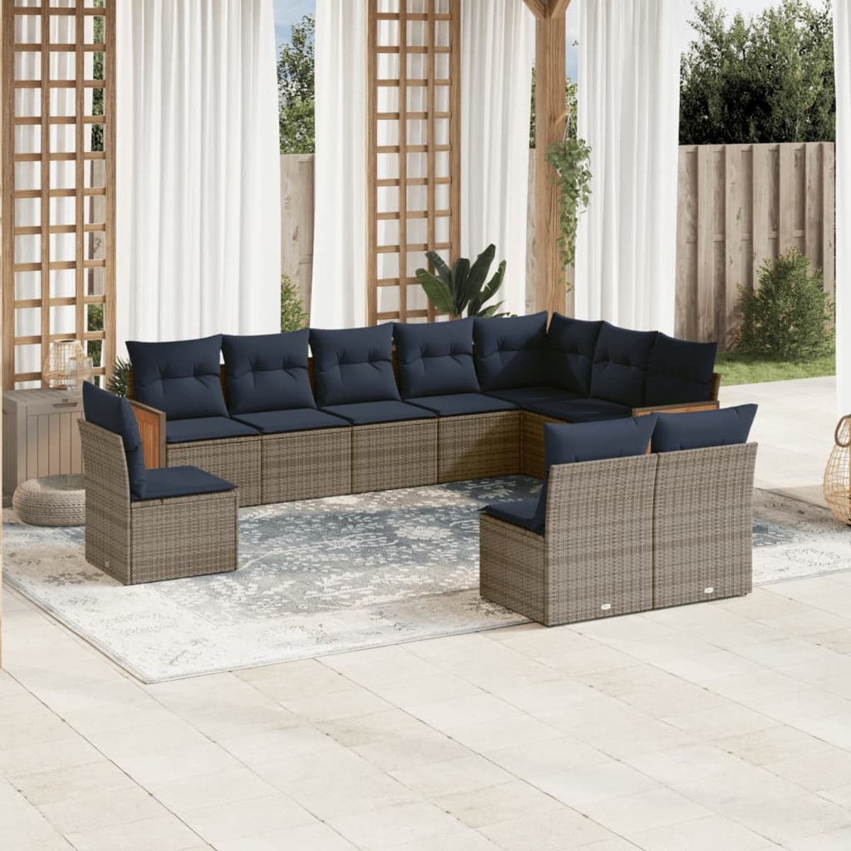 Garten-Sitzgruppe mit blauen Kissen. Korbmöbel auf einem gemusterten Teppich, weißen Vorhängen und Holzpergola.
