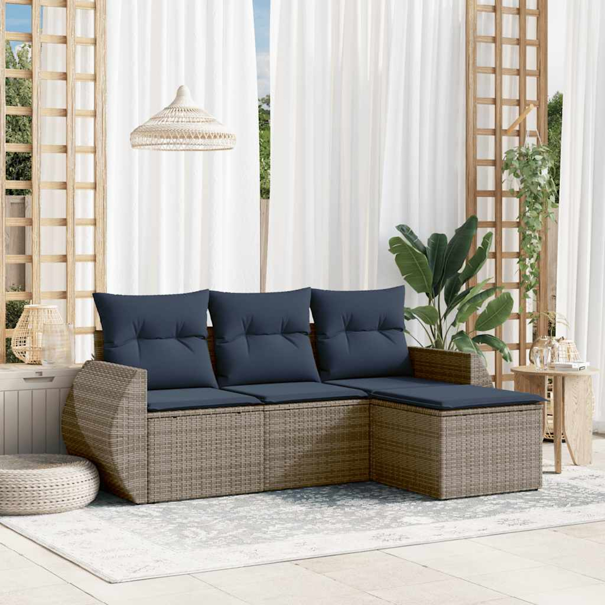 Un sofá de ratán con cojines azules en un patio. Cortinas blancas y enrejado de madera en el fondo.