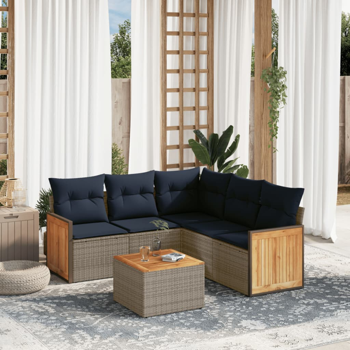 Outdoor-Ecksofa mit marineblauen Kissen und Holztisch steht auf einem gemusterten Teppich. Vorhänge und Pflanzen sind im Hintergrund.
