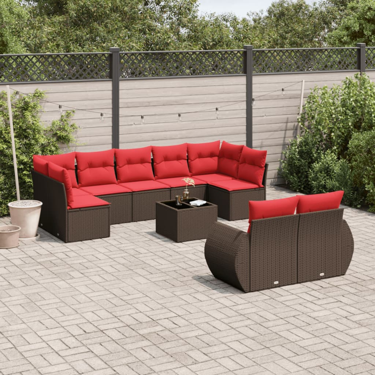 Terrassen-Set mit braunen Korbmöbeln und roten Kissen. Enthält ein Ecksofa, einen Couchtisch und ein Loveseat auf einer gepflasterten Terrasse.