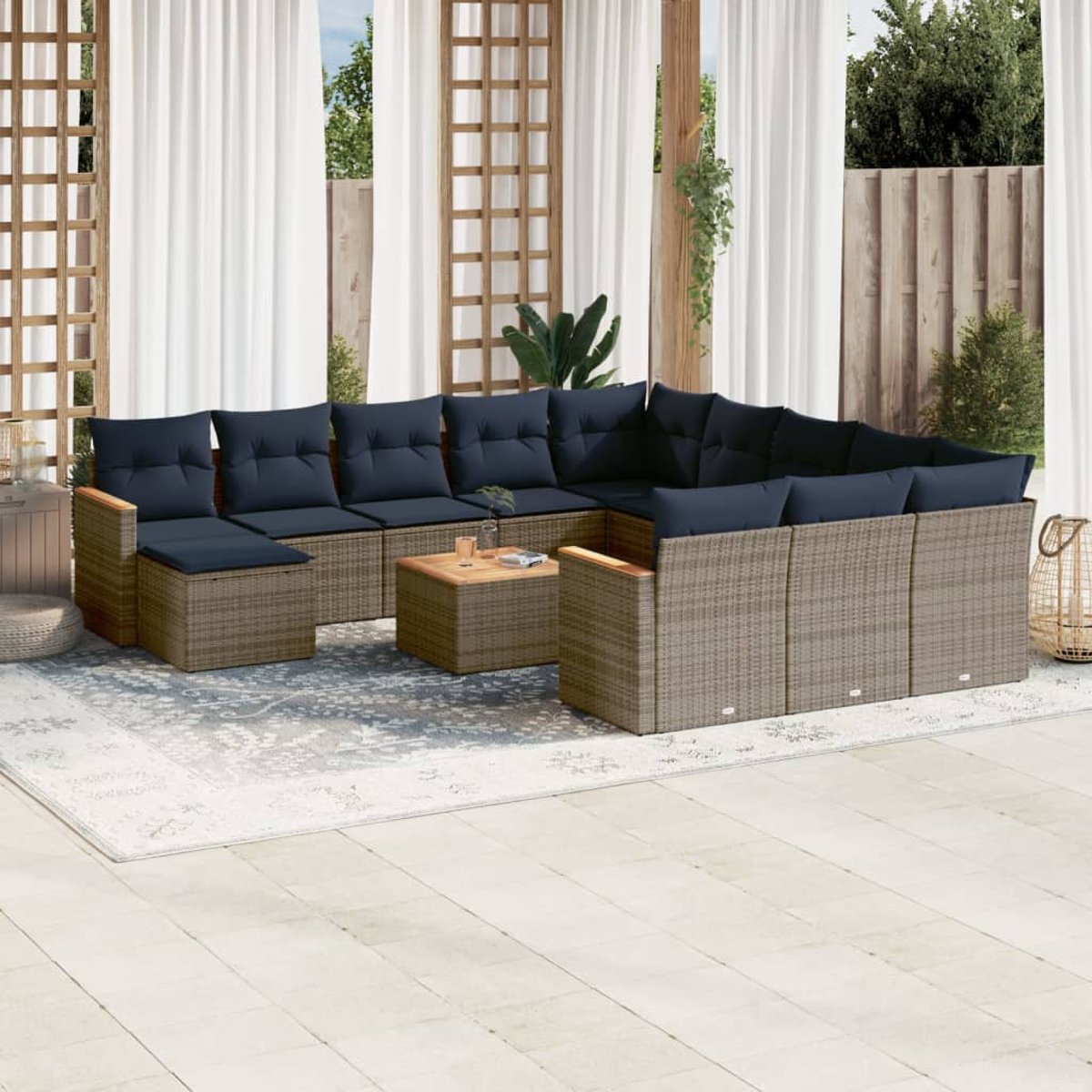 Outdoor-Sitzgruppe mit blauen Kissen, Holztisch und einem Teppich, vor Vorhängen und einem Holzzaun.