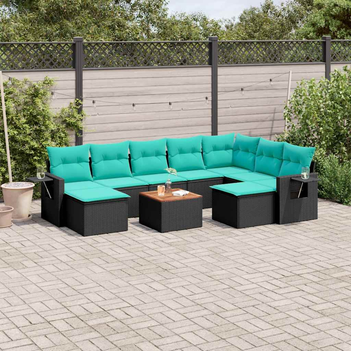 Outdoor-Ecksofa mit türkisfarbenen Kissen und schwarzem Korbgewebe. Kleiner Holztisch davor. Gepflasterte Terrasse und grüne Pflanzen im Hintergrund.