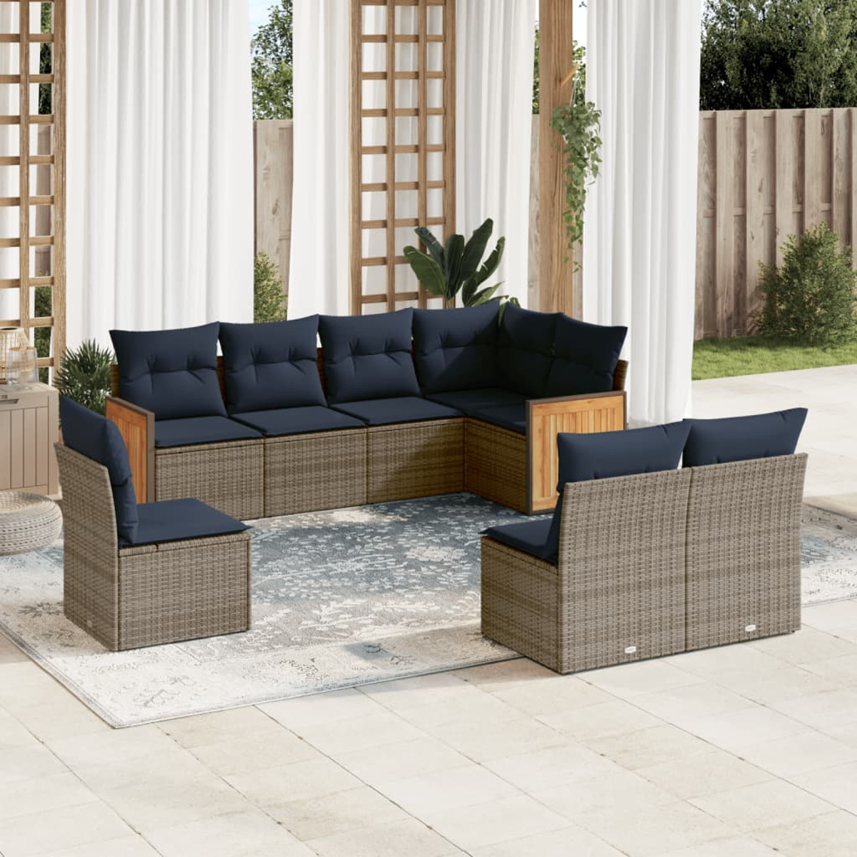 Outdoor-Terrassenset mit Ecksofa, zwei Stühlen und einem Teppich, alles in neutralen Tönen. Dunkelblaue Kissen kontrastieren mit hellbraunen Möbeln.