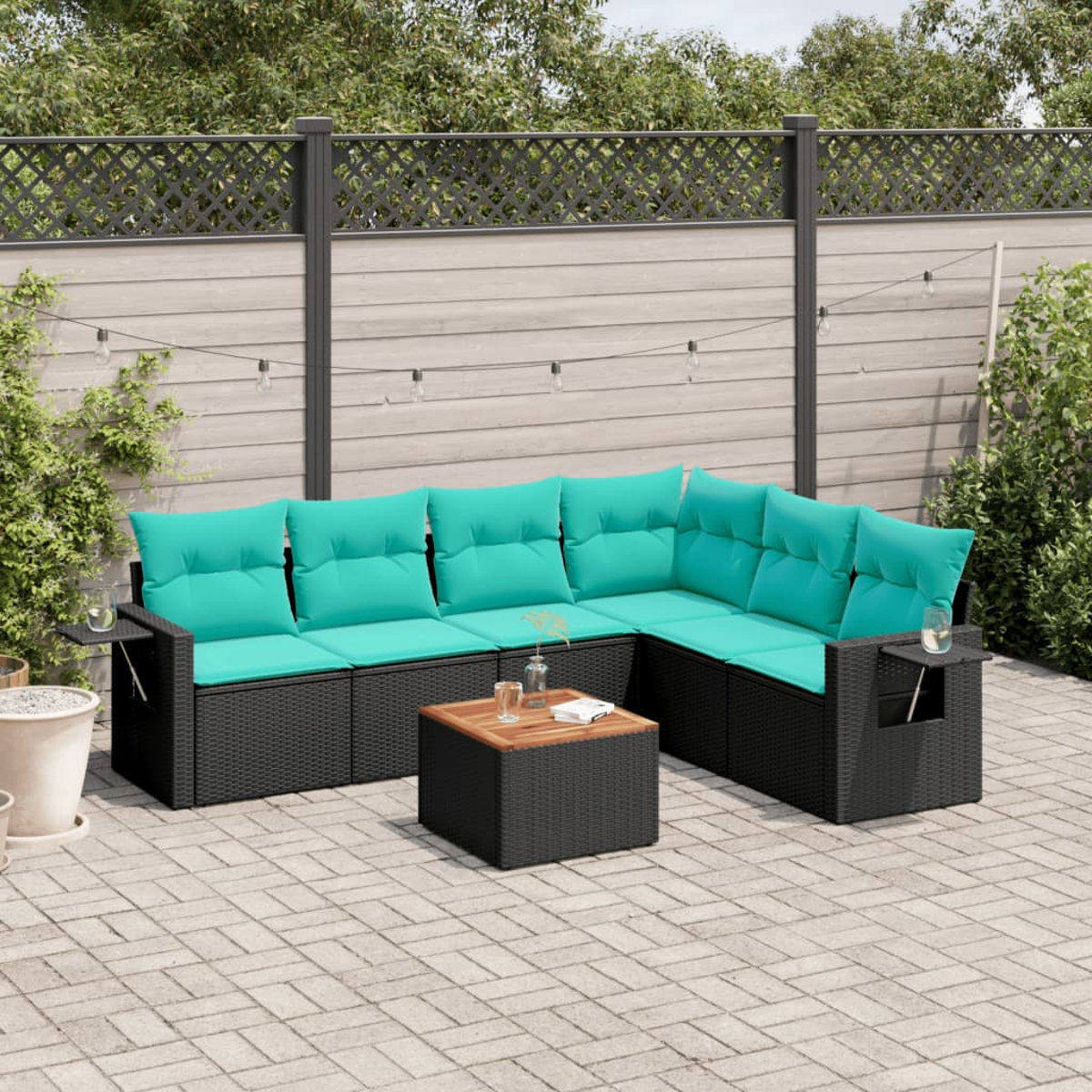 Gartensofa mit türkisfarbenen Kissen und schwarzem Korbgewebe, mit passendem Couchtisch auf einer Terrasse.