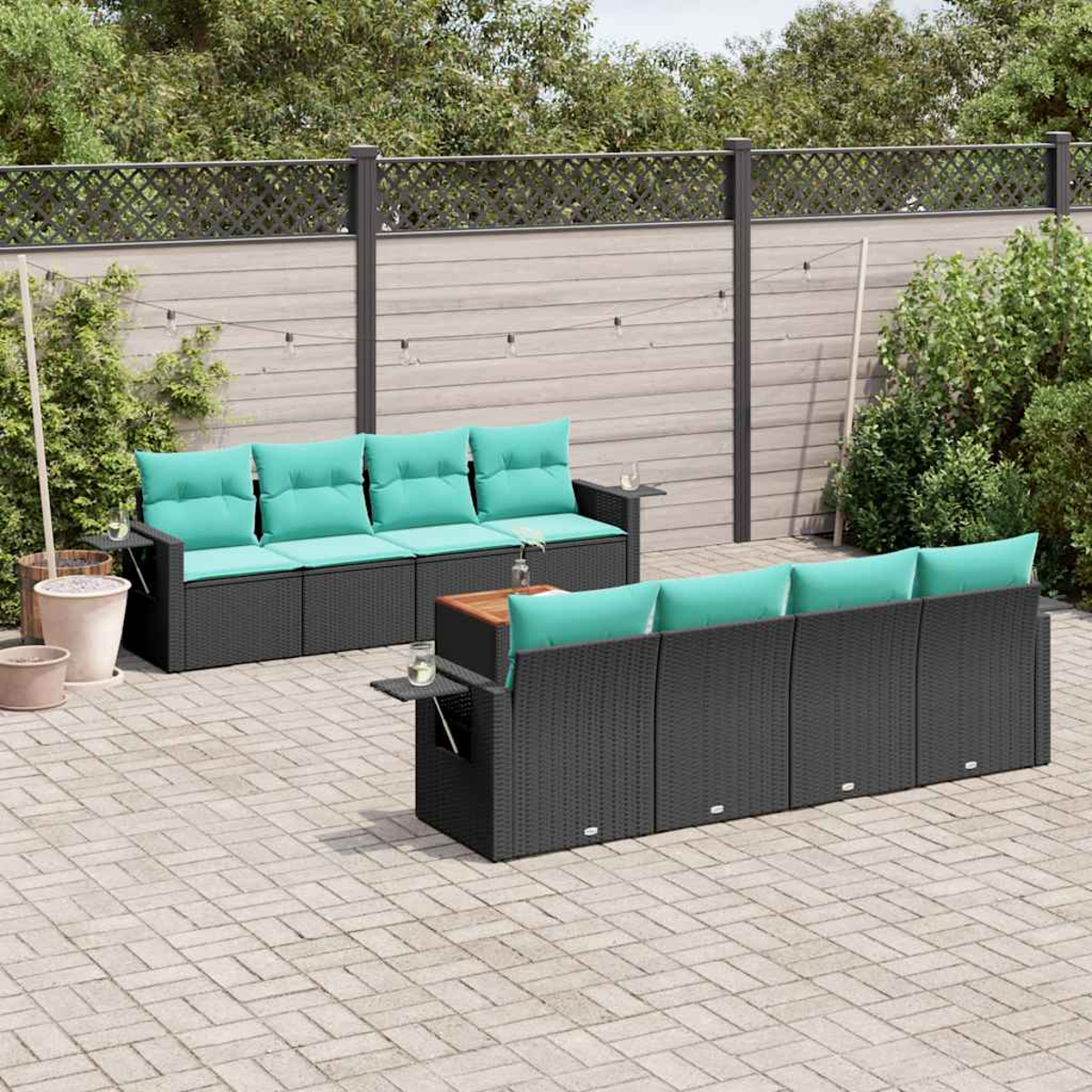 Outdoor-Terrassenset. Schwarze Korbsessel mit türkisfarbenen Kissen. Holztische. Backstein-Terrasse mit Zaun und Grün.