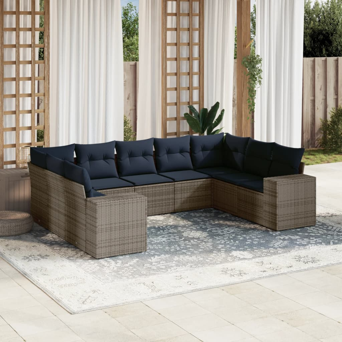 Eine Außenszene mit einem Ecksofa mit marineblauen Kissen auf einem gemusterten Teppich. Weiße Vorhänge und Holzgitter sind im Hintergrund zu sehen.