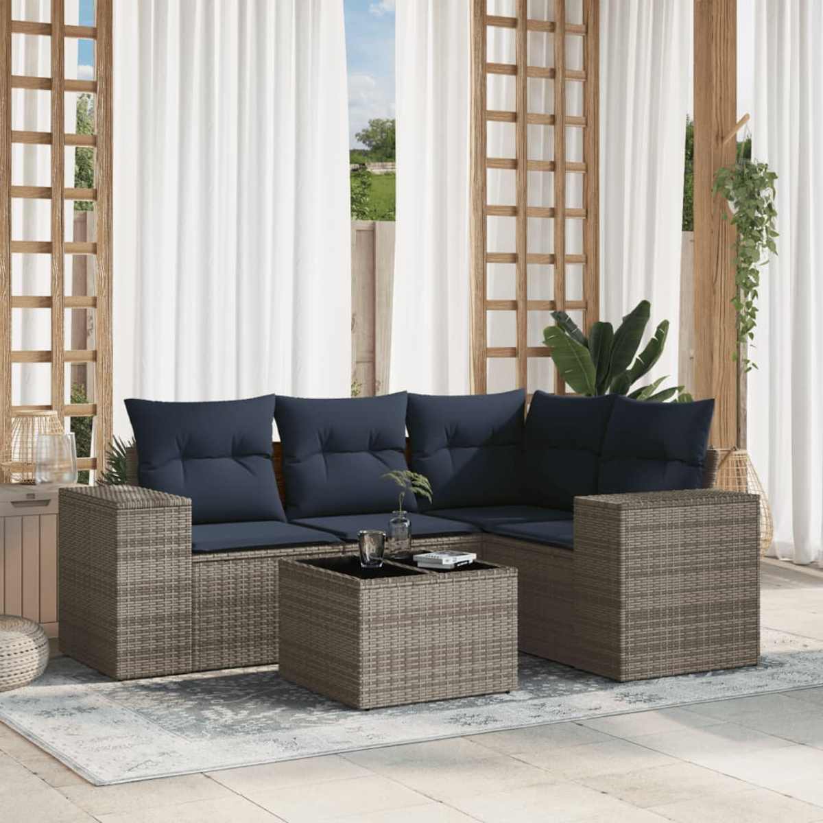 Outdoor-Sitzgruppe mit marineblauen Kissen und einem Couchtisch auf einem Teppich, unter weißen Vorhängen und Holzrahmen.