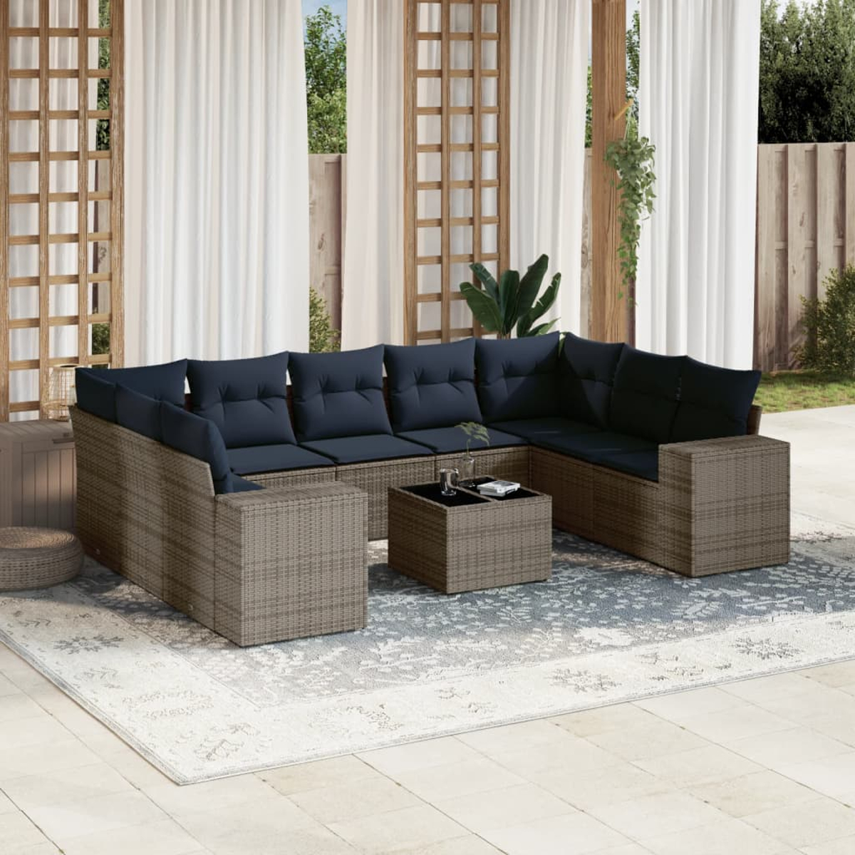 Outdoor-Ecksofa mit marineblauen Kissen, Couchtisch und Teppich. Weiße Vorhänge im Hintergrund. Patio-Einstellung.