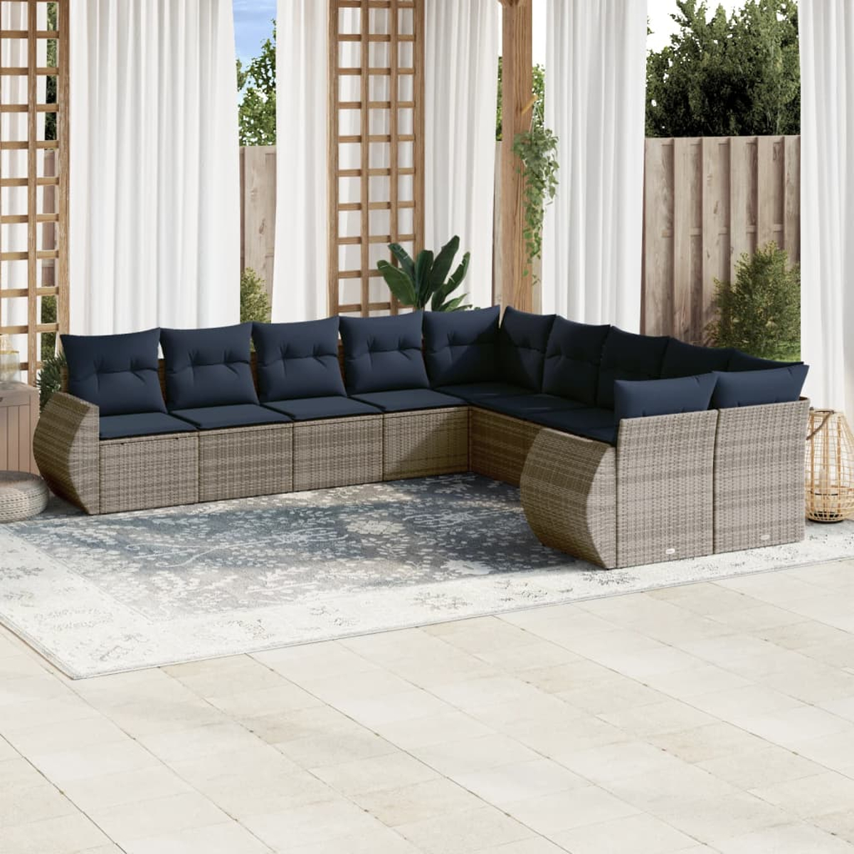 Outdoor-Ecksofa mit marineblauen Kissen auf einem gemusterten Teppich. Dahinter weiße Vorhänge und Holzgitter.