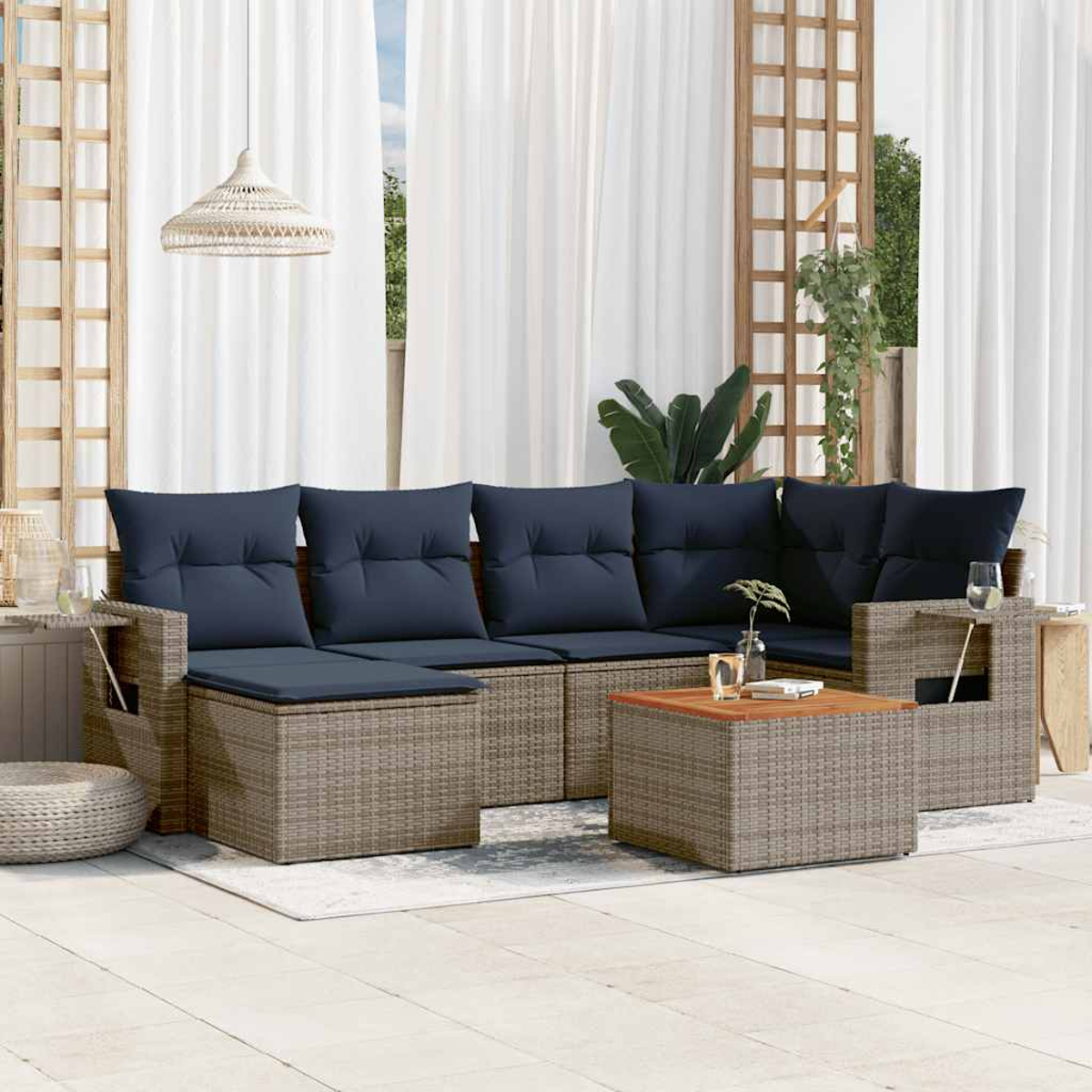 Terrassenset mit marinefarbenen Kissen. Enthält Sofa, Tisch und Beistelltische. Weiße Vorhänge und Holzgitter im Hintergrund.