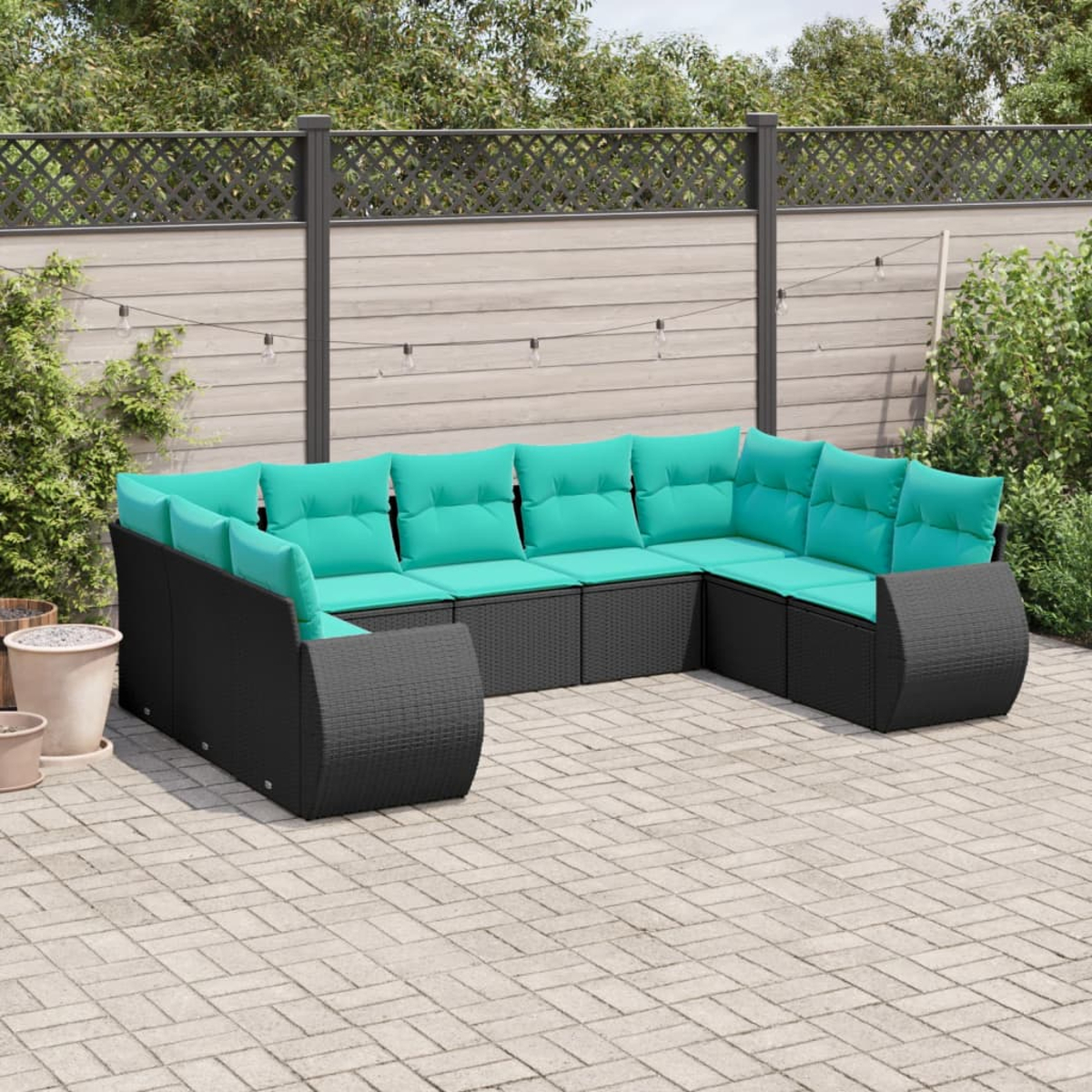 Ein Ecksofa für den Außenbereich mit schwarzem Webrahmen und türkisfarbenen Kissen auf einer Ziegelterrasse. Im Hintergrund befinden sich ein Zaun und Grün.
