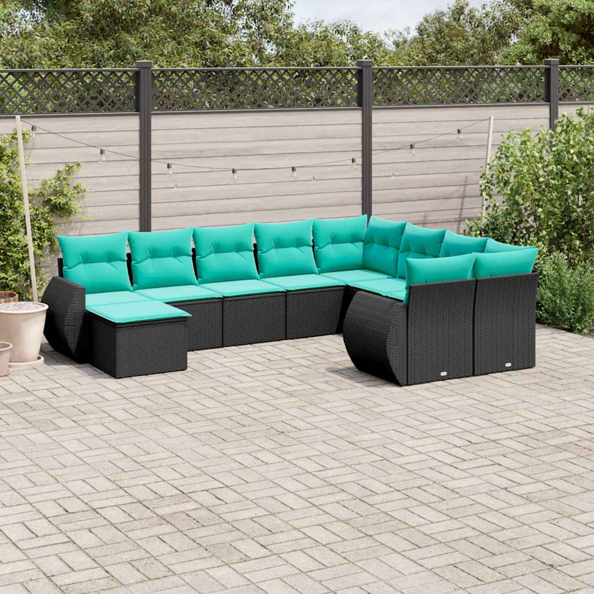Schwarzes Ecksofa mit türkisfarbenen Kissen auf einer gepflasterten Terrasse. Ein Zaun und Pflanzen befinden sich im Hintergrund.