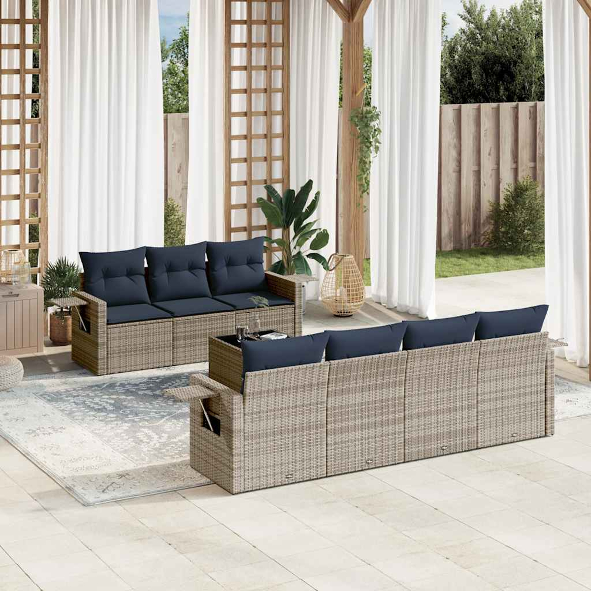 Terrassenset mit gewebten Sofas, marineblauen Kissen und weißen Vorhängen. Ein Teppich, Pflanzen und eine Holzpergola ergänzen die Einrichtung.