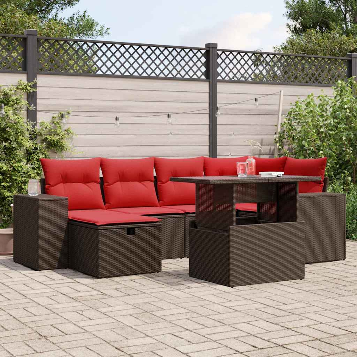 Garten-Sitzgruppe mit roten Kissen und einem braunen Tisch auf einer Terrasse. Im Hintergrund ein Zaun und Grün.