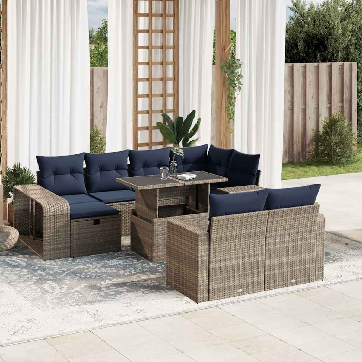 Outdoor-Terrassenset mit Korbmöbeln und marineblauen Kissen. Enthält einen Tisch und einen Teppich. Der Hintergrund hat Vorhänge und Pflanzen.
