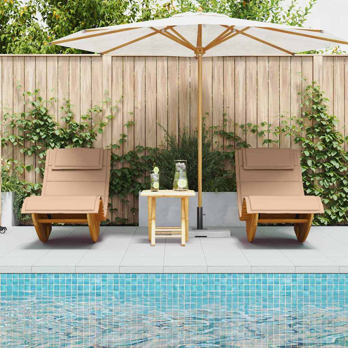 Dos tumbonas beige, una mesita con bebidas y un soporte para sombrillas cerca de una piscina. Valla de madera en el fondo con enredaderas.