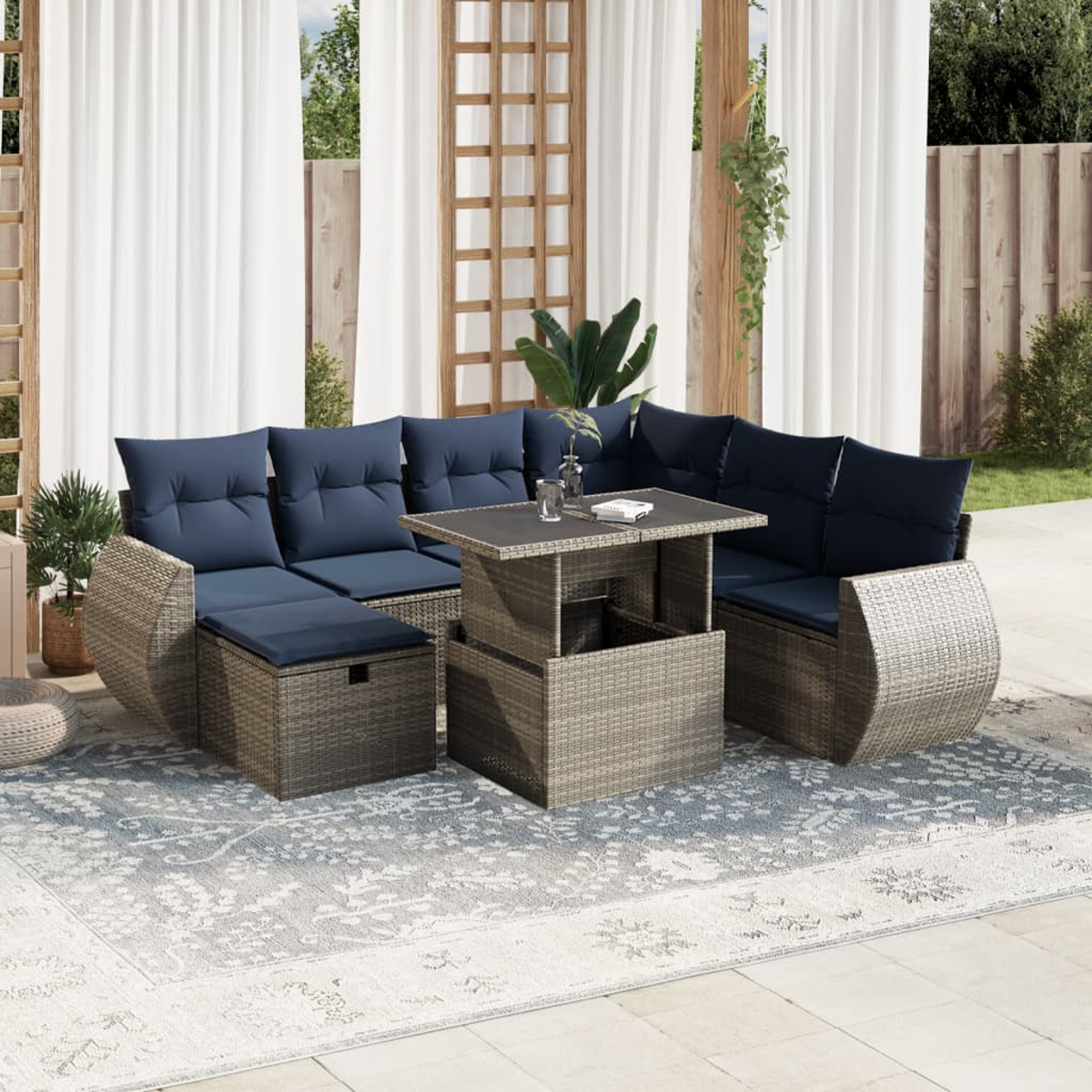 Garten-Terrassenset mit blauen Kissen, einem grauen Tisch und einem gemusterten Teppich. Weiße Vorhänge und Holzstruktur im Hintergrund.