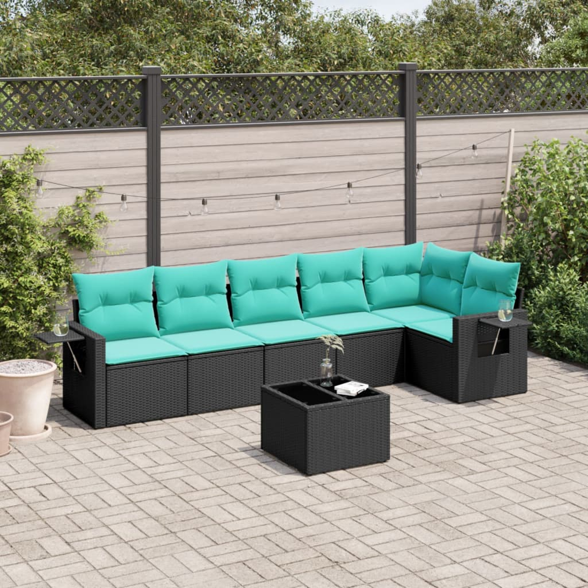 Outdoor-Sitzgruppe aus schwarzem Korbgeflecht mit türkisfarbenen Kissen, kleinem Tisch und quadratischem Couchtisch auf einer Ziegelterrasse.