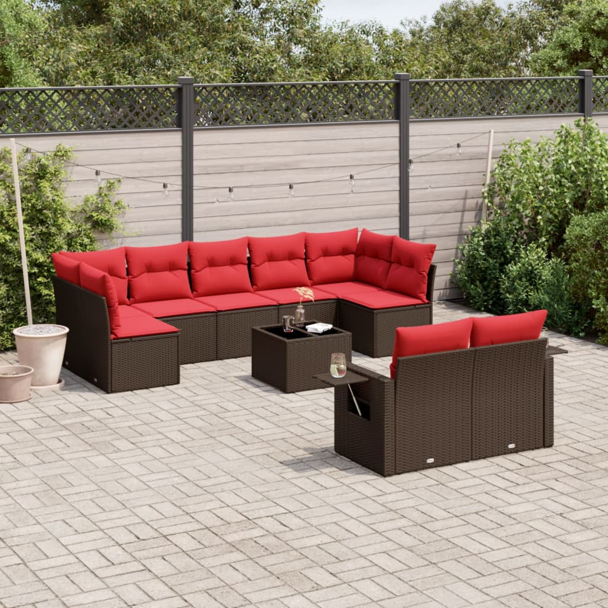 Garten-Sitzgruppe mit roten Kissen. Enthält ein Ecksofa, einen kleinen Tisch und eine Couch, auf einer Terrasse mit Zaunhintergrund.