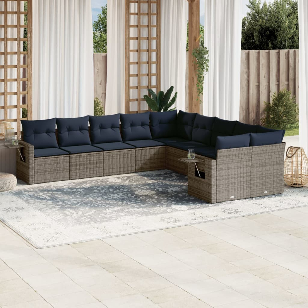 Ein Ecksofa im Freien mit marineblauen Kissen steht auf einem gemusterten Teppich. Der Hintergrund zeigt weiße Vorhänge und eine Holzkonstruktion.